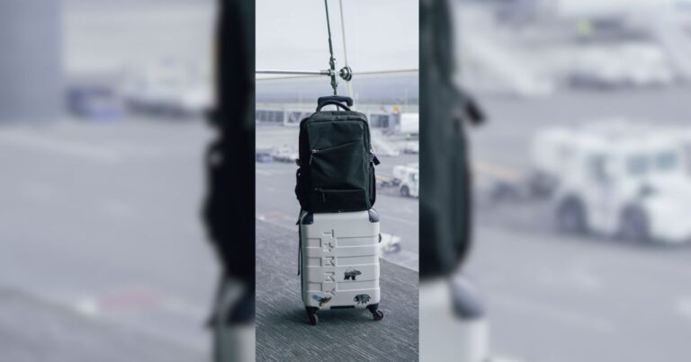 White carry-on suitcase with black backpack in an airport terminal